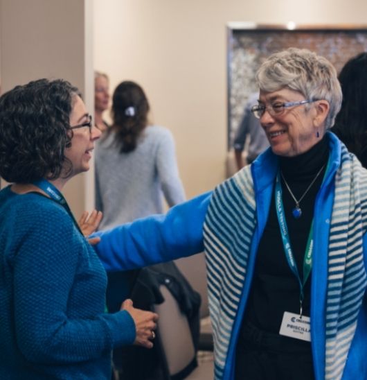 two women wearing blue smiling while practicing muscle testing