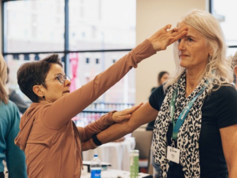 woman practicing muscle testing with her hand on the other woman's forehead