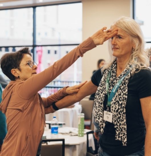 woman practicing muscle testing with her hand on the other woman's forehead